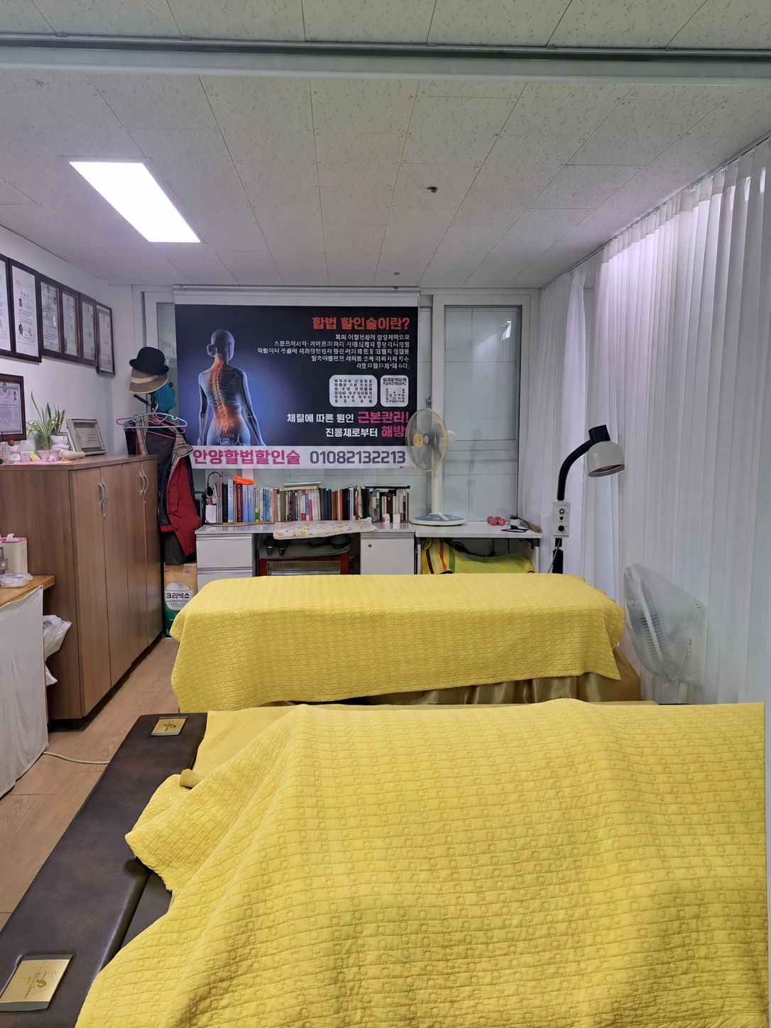 노란색으로 침구 색상을 보정한 관리 침대 두 개와 커튼, 주변 기기가 보이는 늘푸른 관리실